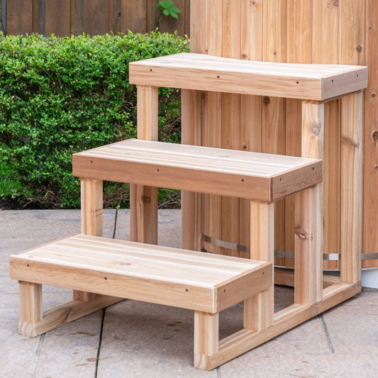 Three-tier steps made from knotty red cedar, designed for accessing a cold plunge. The steps feature a natural wood finish, showcasing the unique grain patterns and warm tones of the cedar, arranged in a sturdy, functional design.