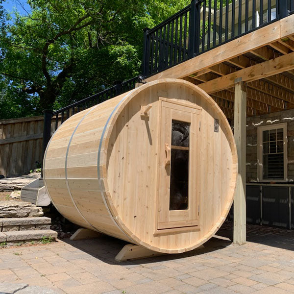 Semi-side view of a Harmony Barrel Sauna beside the stairs.