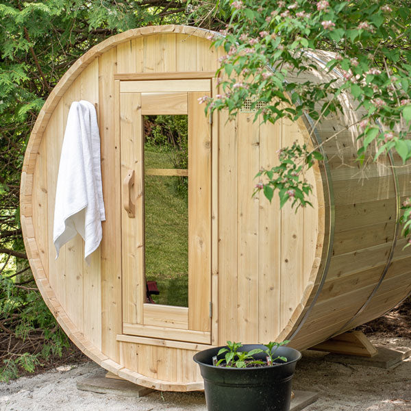 View of the front door of a Harmony Barrel Sauna under tree branches.