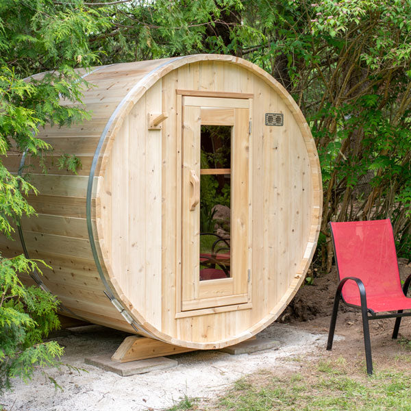 Front and side view of a Harmony Barrel Sauna surrounded by trees.