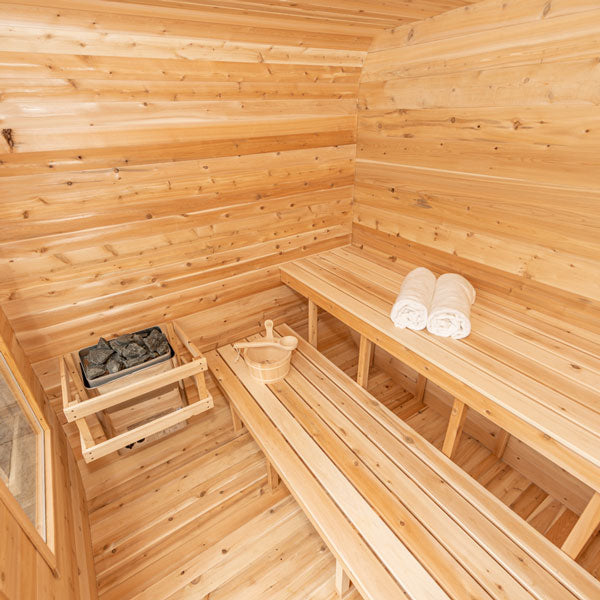 Inside top angle view of a Canadian Timber Luna Sauna, featuring a sauna heater on one side, two benches, and additional accessories.
