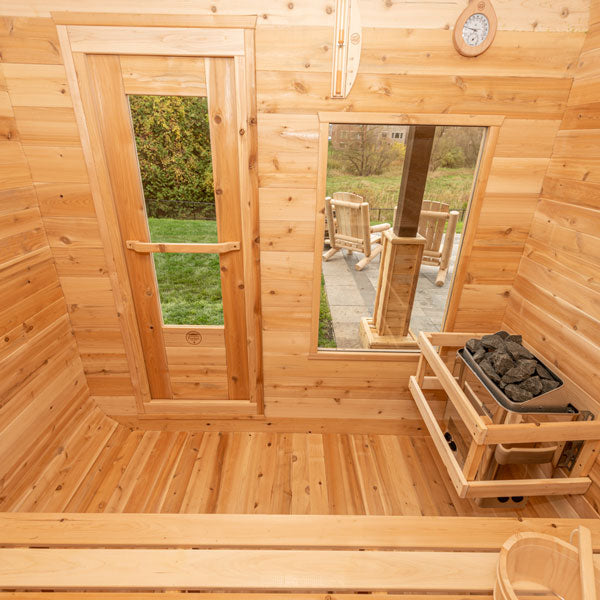 Inside view of a Canadian Timber Luna Sauna, featuring a door and windows, with a sauna heater in the corner.