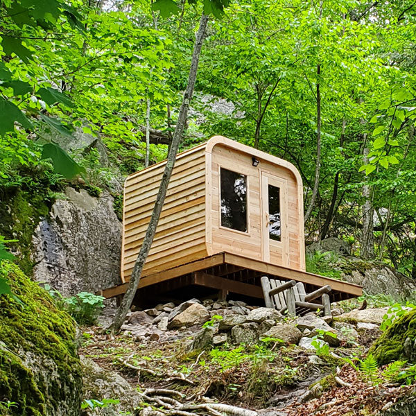 Front and left side view of a Canadian Timber Luna Sauna, positioned above the rocks.