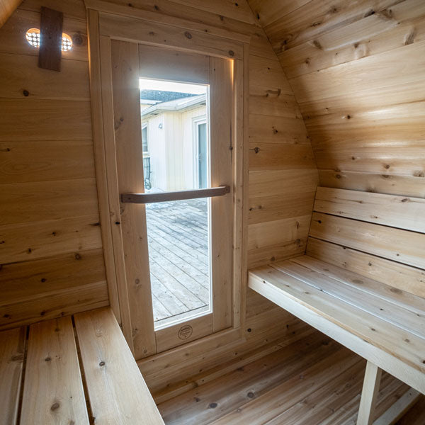 Inside view of a Mini POD Sauna with two benches on each side and a glass door at the front.