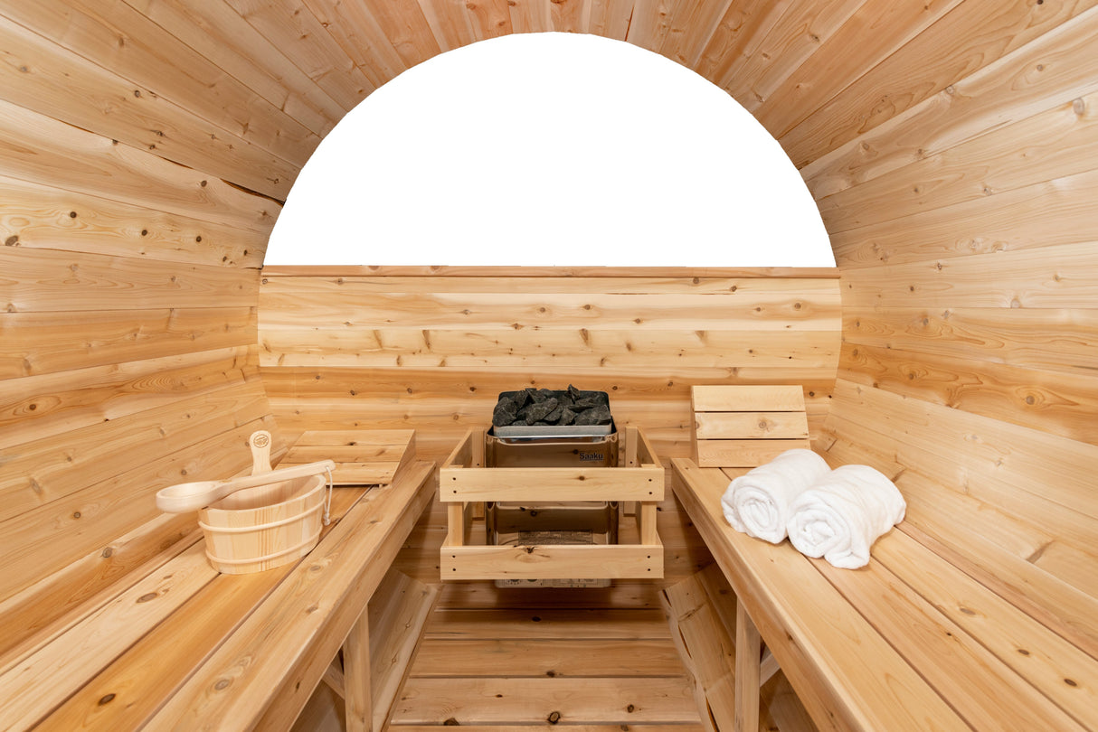 Inside center view of the Serenity MP Barrel Sauna, featuring a sauna heater at the center, two benches on each side, and a half-moon glass window at the back.