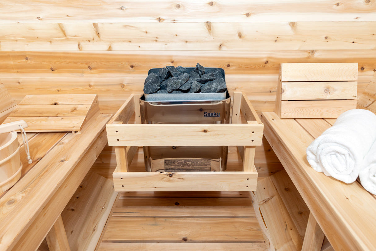 Inside view of the Serenity MP Barrel Sauna, featuring a sauna heater at the center and two benches on each side.