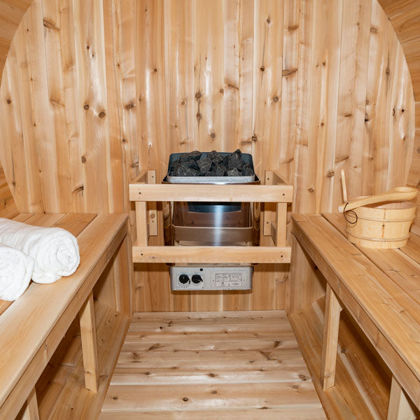 Inside view of a Serenity Barrel Sauna, featuring a sauna heater in the center and two benches.