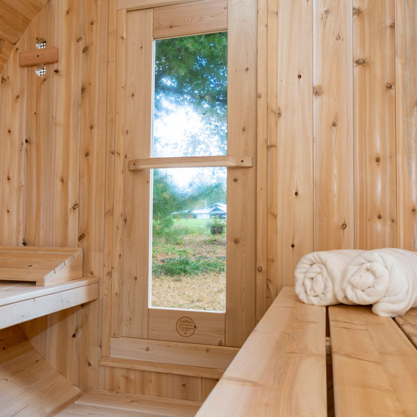 Inside view of a Serenity Barrel Sauna, featuring a glass door and benches.