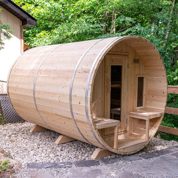 Front and left side view of a tranquility barrel sauna with a porch, glass windows, and doors.