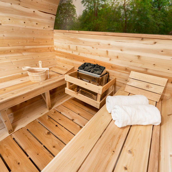 Inside view of the Tranquility MP Barrel Sauna, featuring sauna heaters and two benches on each side.