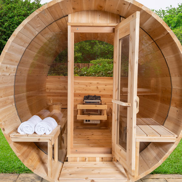 Front view of the Tranquility MP Barrel Sauna with an open glass door and porch, highlighting the sauna heaters inside.