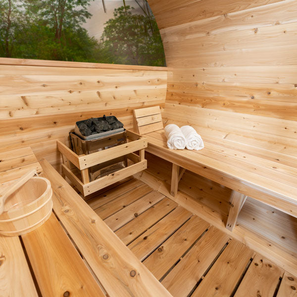 Inside view of the Tranquility MP Barrel Sauna from the left angle, showcasing the sauna heater in the center and two benches.