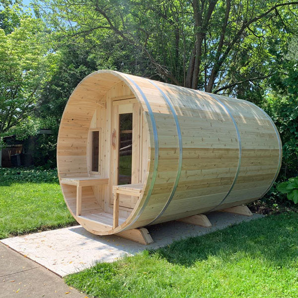 Front and side view of a tranquility barrel sauna featuring a porch, glass windows, and doors.