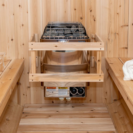 Front view of an electric sauna heater filled with rocks, shown from a distance. The heater features a sleek, modern design, with stones placed on top to enhance the sauna experience by generating steam when water is applied.
