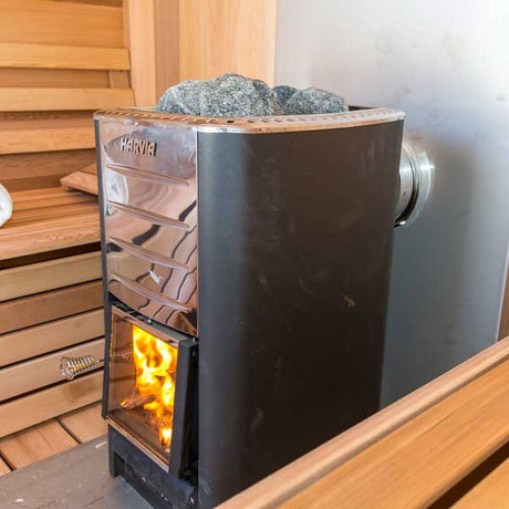Top front view of a wood-fired sauna heater featuring rocks placed on top for heat retention.