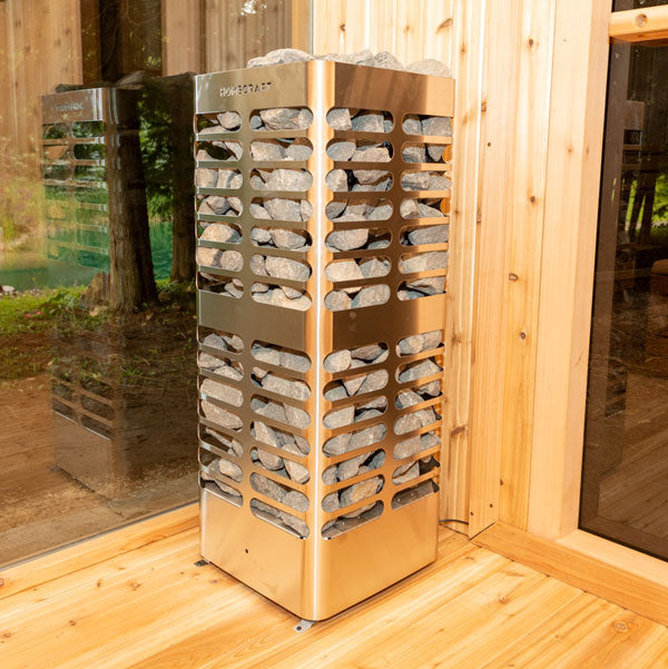 Front and side view of the Homecraft Revive 6kW electric sauna heater positioned near a glass wall and a wooden wall.