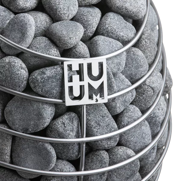 Close-up view of the HUUM Drop electric sauna heater highlighting its stainless steel finish and sauna rocks.