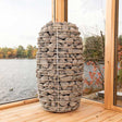 Huum Hive Mini sauna heater model HIVE Mini positioned in front of a tranquil lake, showcasing its compact design in a natural setting.