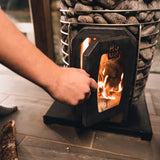 Semi-open view of the Huum Hive wood burning sauna heater model HIVEWOOD, highlighting the interior and wood storage area.