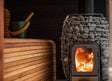 Wood burning inside a Huum wood heater, with rocks positioned on top for added insulation.