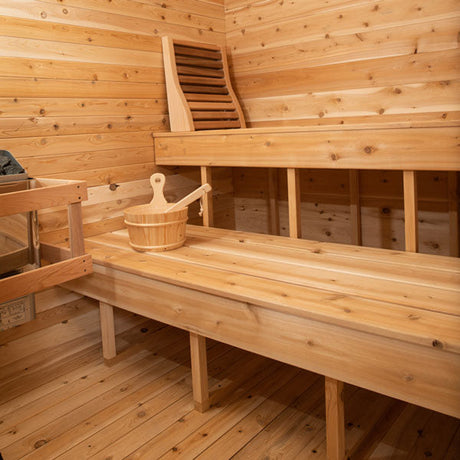 Inside view of a Canadian Timber Luna Sauna, featuring a sauna heater on one side, two benches, and additional accessories.